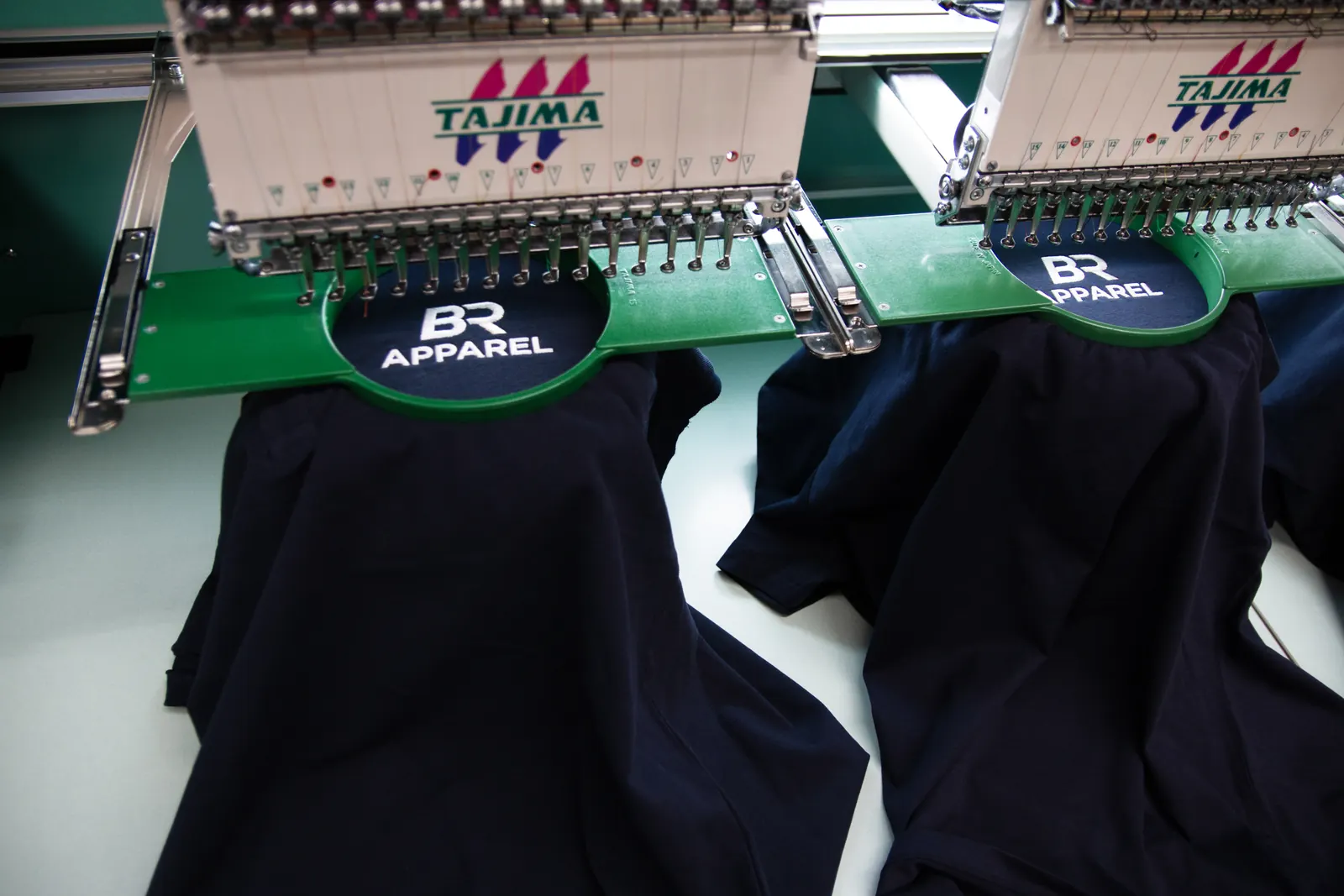 Logo being embroidered onto navy polo shirts on the production line