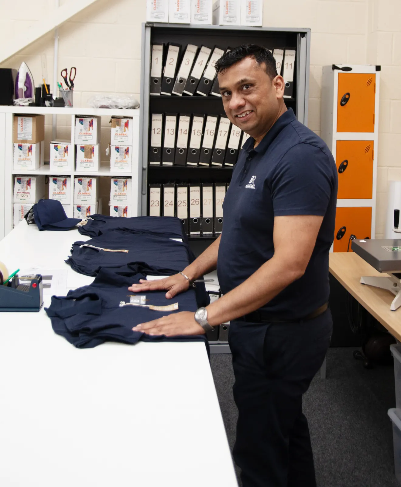 Stack of folded branded navy garments at BR Apparel in Bradford