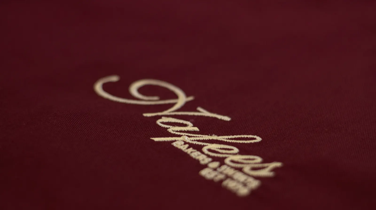 Close-up of gold embroidery on a maroon hospitality uniform