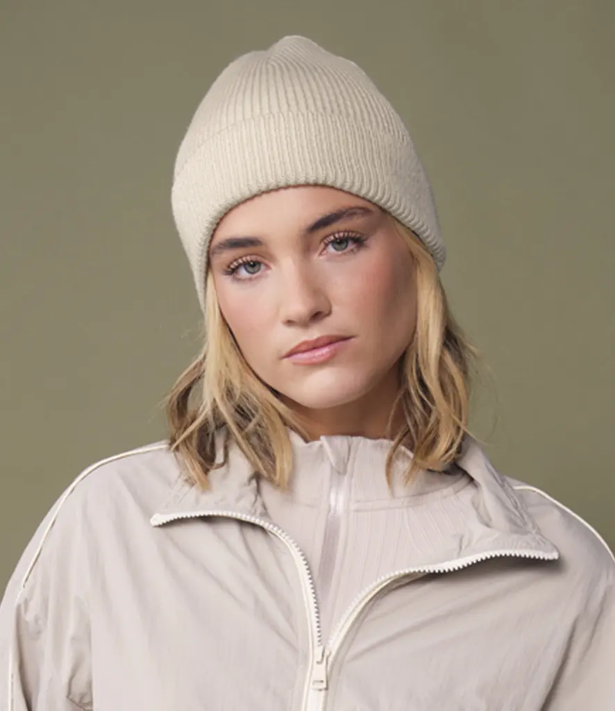 Model wearing a plain cream ribbed cuffed beanie