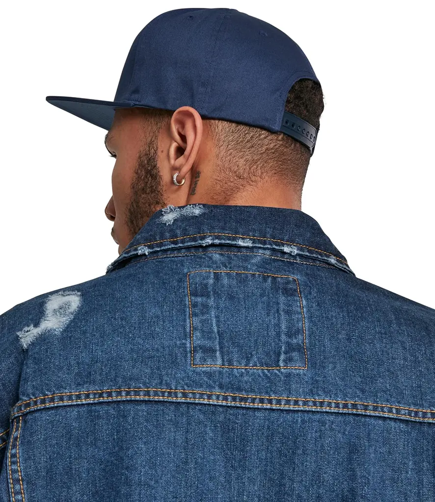 Back view of a model in a denim jacket wearing a plain navy flat peak cap