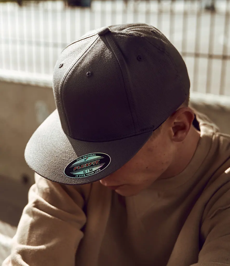 Model wearing a plain dark flat peak cap with a flat brim
