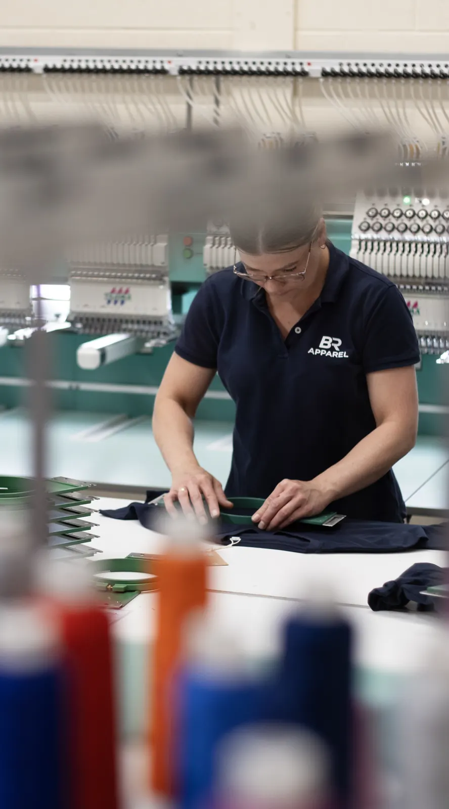 Embroidery thread cones and an operator at work in the BR Apparel unit