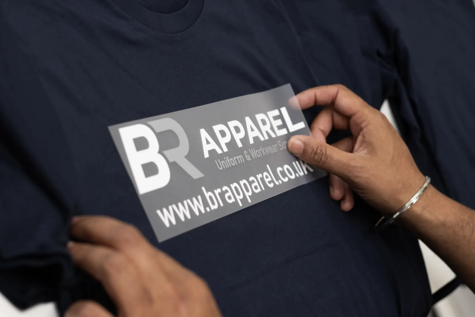 Printed transfer being positioned on a navy garment at BR Apparel